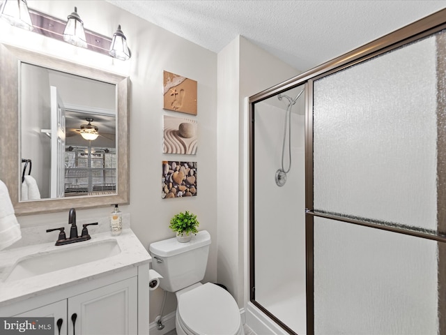 full bath featuring a shower stall, toilet, vanity, a textured ceiling, and ceiling fan
