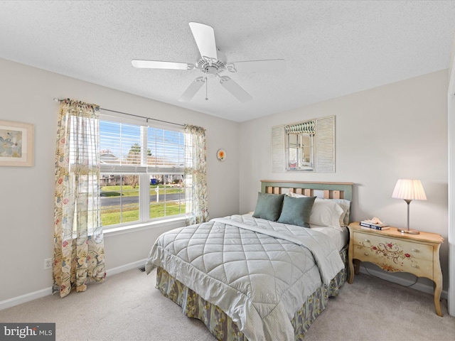 carpeted bedroom featuring a textured ceiling, a ceiling fan, and baseboards