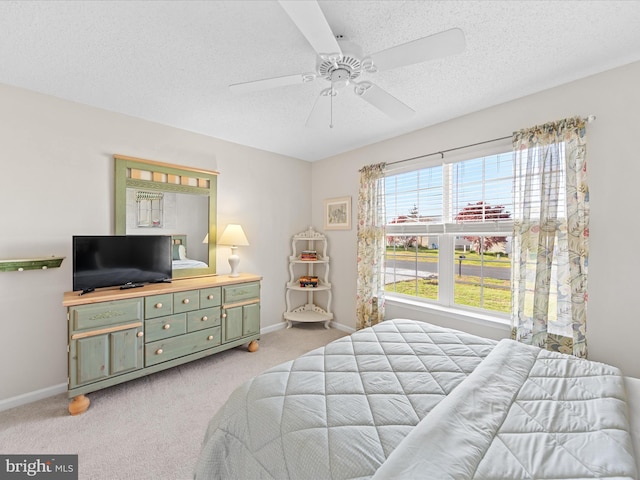 bedroom featuring light carpet, a ceiling fan, baseboards, and a textured ceiling