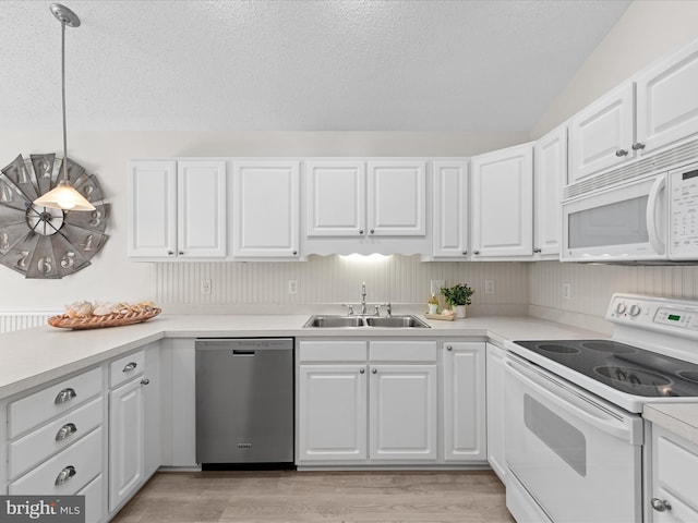 kitchen featuring light wood finished floors, a sink, white appliances, a textured ceiling, and white cabinetry