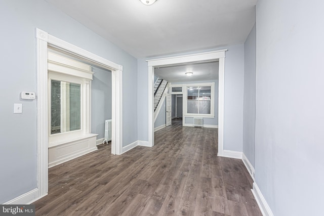 hall featuring baseboards, visible vents, dark wood-style floors, and radiator