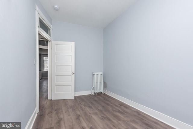 unfurnished bedroom featuring baseboards, dark wood finished floors, and radiator heating unit