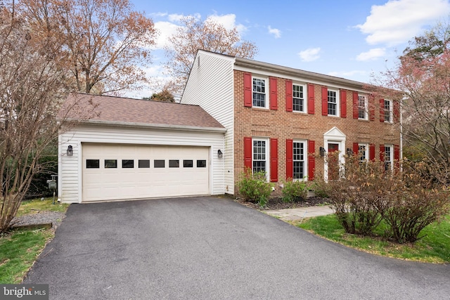colonial-style house featuring brick siding, driveway, and a garage