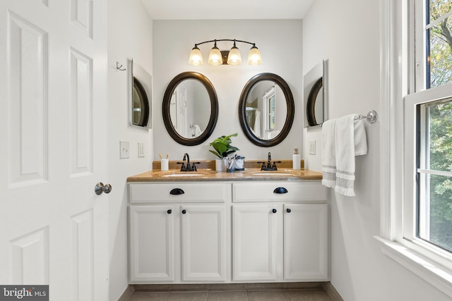 bathroom with double vanity, baseboards, and a sink
