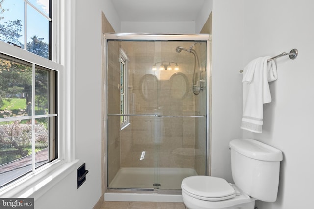 bathroom with a shower stall, toilet, and tile patterned floors