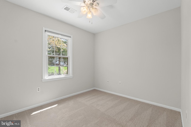 carpeted spare room with baseboards, a ceiling fan, and visible vents