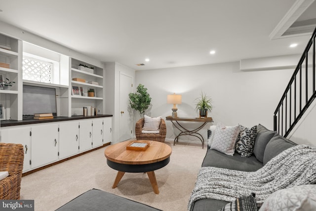 living area featuring built in shelves, light carpet, stairs, and recessed lighting