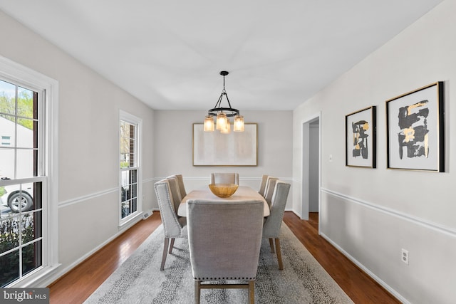dining room featuring baseboards, wood finished floors, and an inviting chandelier