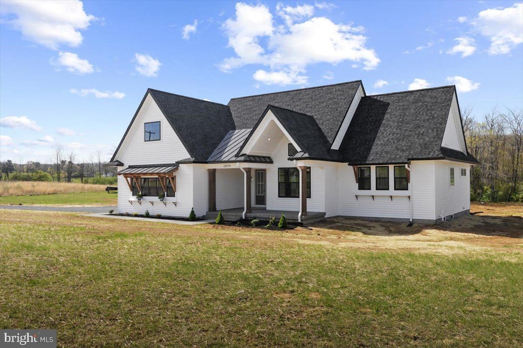 modern farmhouse style home featuring a front lawn, a shingled roof, a porch, metal roof, and a standing seam roof