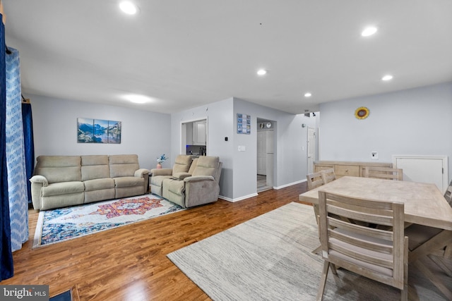 living area with baseboards, wood finished floors, and recessed lighting