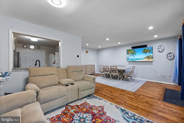 living area featuring baseboards, wood finished floors, and recessed lighting
