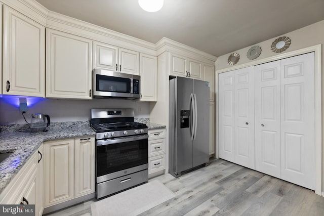 kitchen featuring stainless steel appliances, light wood-style floors, and light stone counters