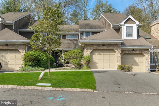 townhome / multi-family property featuring stone siding, a shingled roof, and a front yard