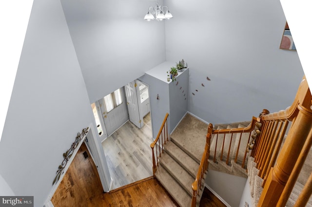 stairs featuring a chandelier and wood finished floors