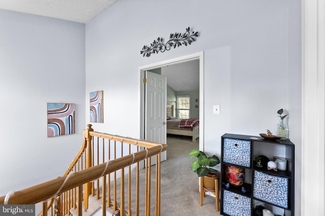 corridor with an upstairs landing and carpet
