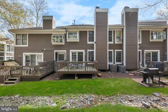 back of house featuring a wooden deck, a chimney, a yard, and cooling unit