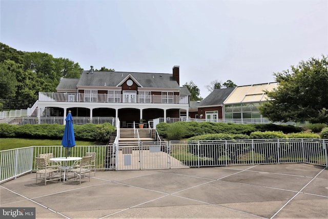 back of house with stairway, a balcony, a chimney, fence, and a patio