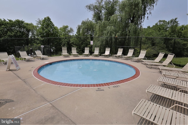community pool with a patio area and fence