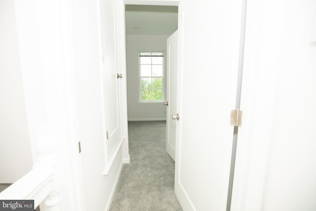 hallway featuring light carpet and baseboards