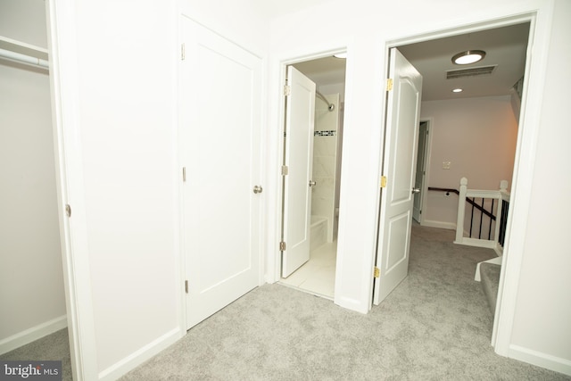 interior space featuring light carpet, an upstairs landing, visible vents, and baseboards