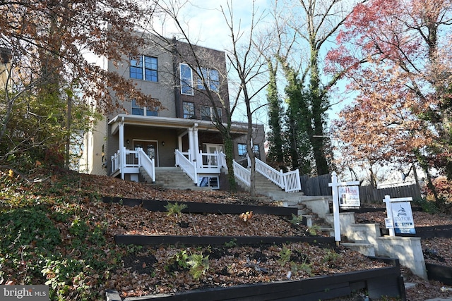 view of front of house with fence, covered porch, and stairs