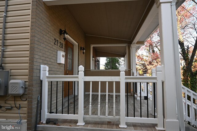 view of exterior entry featuring brick siding and covered porch