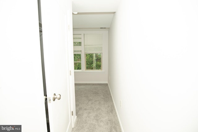 corridor featuring baseboards and carpet