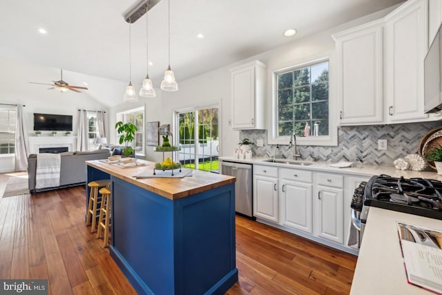 kitchen with white cabinets, a sink, appliances with stainless steel finishes, ceiling fan, and butcher block counters