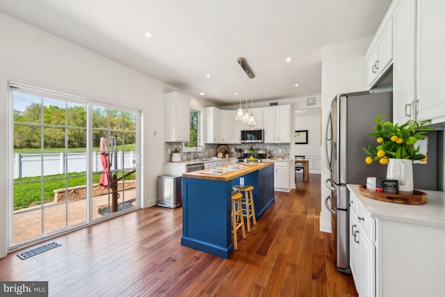 kitchen with white cabinetry, wood counters, appliances with stainless steel finishes, and a kitchen island