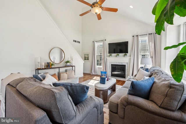 living area with visible vents, high vaulted ceiling, wood finished floors, ceiling fan, and a fireplace