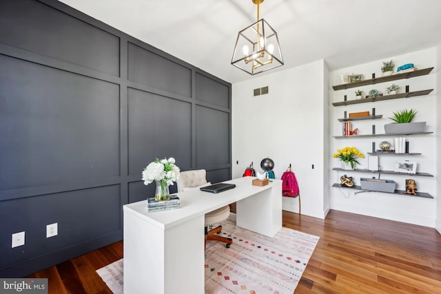 office featuring baseboards, visible vents, wood finished floors, and a notable chandelier