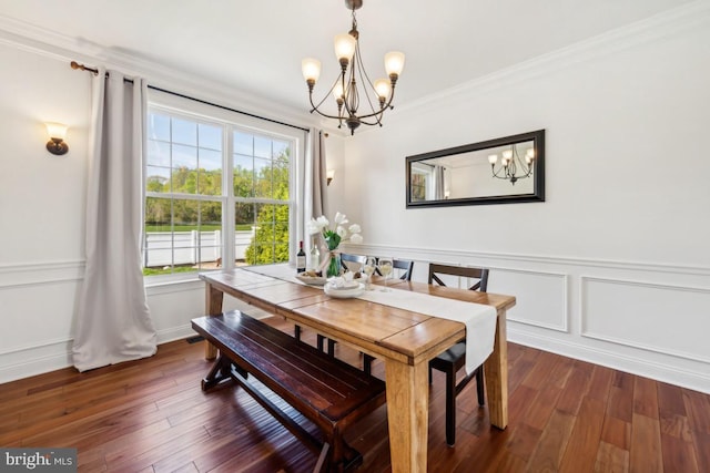 dining space with wood-type flooring, ornamental molding, a notable chandelier, and a wainscoted wall