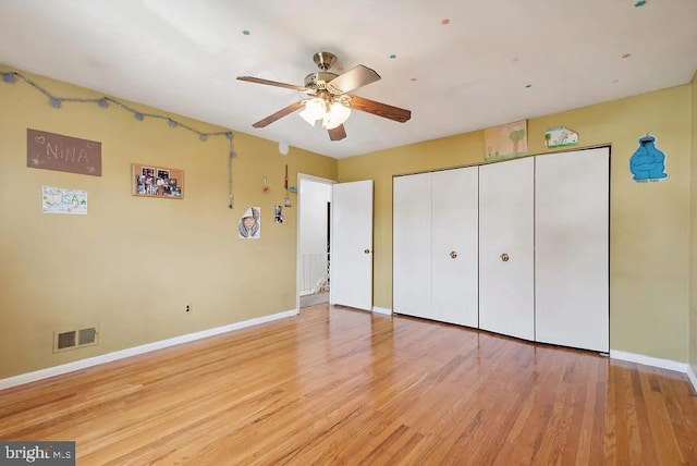 unfurnished bedroom featuring light wood-style flooring, visible vents, a closet, baseboards, and a ceiling fan