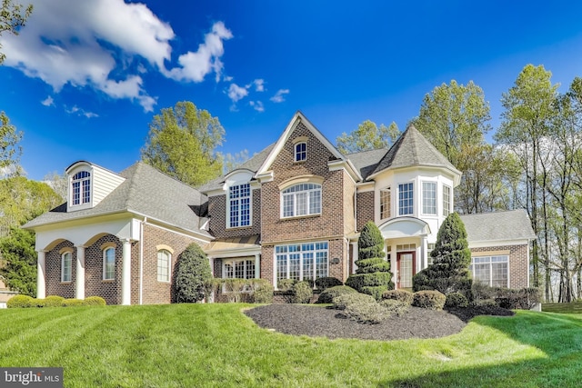 view of front of home featuring brick siding, a shingled roof, and a front lawn