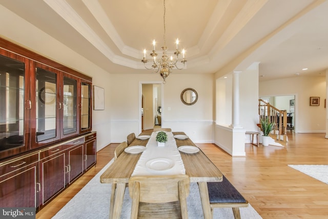 dining space featuring an inviting chandelier, light wood-style floors, a raised ceiling, and crown molding