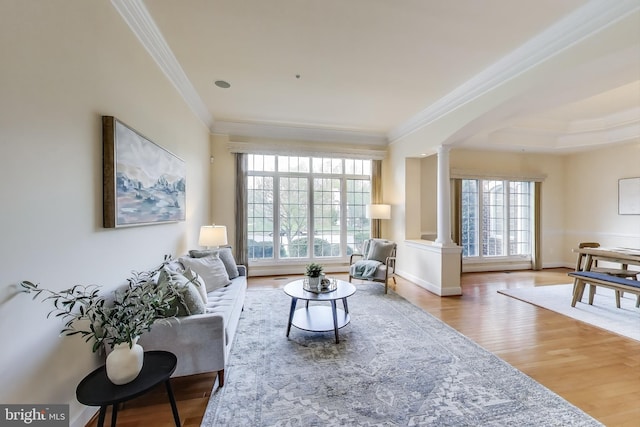 living area with plenty of natural light, crown molding, wood finished floors, and decorative columns