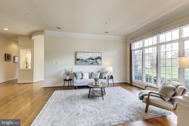 living area featuring plenty of natural light, crown molding, and wood finished floors