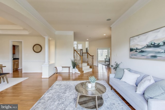 living room featuring ornamental molding, wood finished floors, stairs, and decorative columns