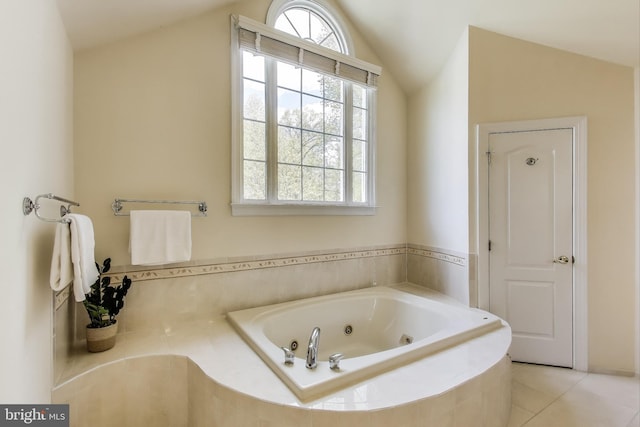bathroom with lofted ceiling, a jetted tub, and tile patterned flooring