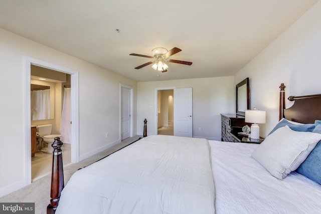 carpeted bedroom with ensuite bath, baseboards, and a ceiling fan