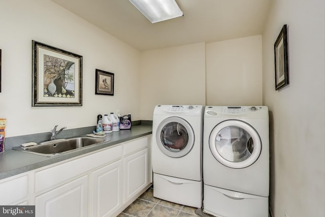 clothes washing area featuring washing machine and clothes dryer, a sink, and cabinet space