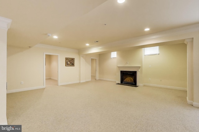 finished basement featuring a fireplace with flush hearth, light carpet, recessed lighting, and ornamental molding