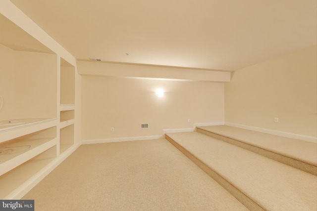 basement with baseboards, carpet flooring, visible vents, and built in features