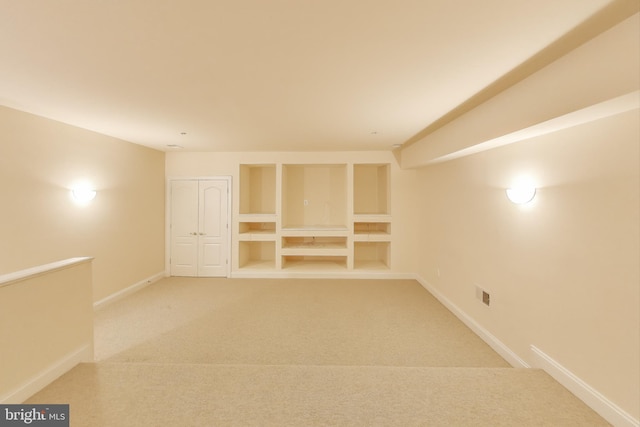 below grade area with light carpet, visible vents, and baseboards