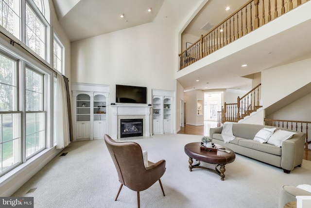 living room featuring a fireplace with flush hearth, a high ceiling, and a wealth of natural light