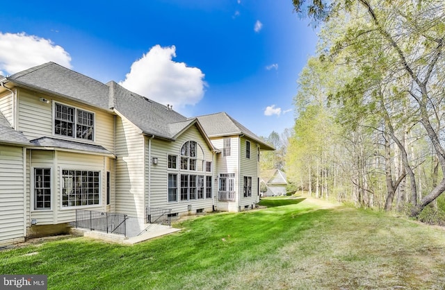 rear view of house with a yard and a shingled roof