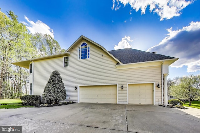 view of side of home with an attached garage, driveway, and a shingled roof
