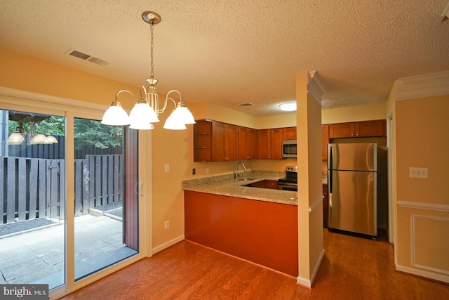 kitchen featuring visible vents, wood finished floors, a sink, a chandelier, and stainless steel appliances