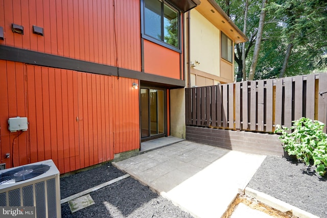entrance to property with fence, cooling unit, and a patio area