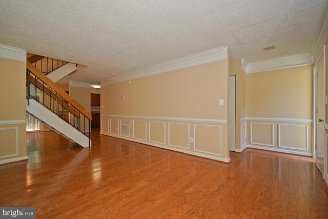 unfurnished room with crown molding, a decorative wall, and a textured ceiling
